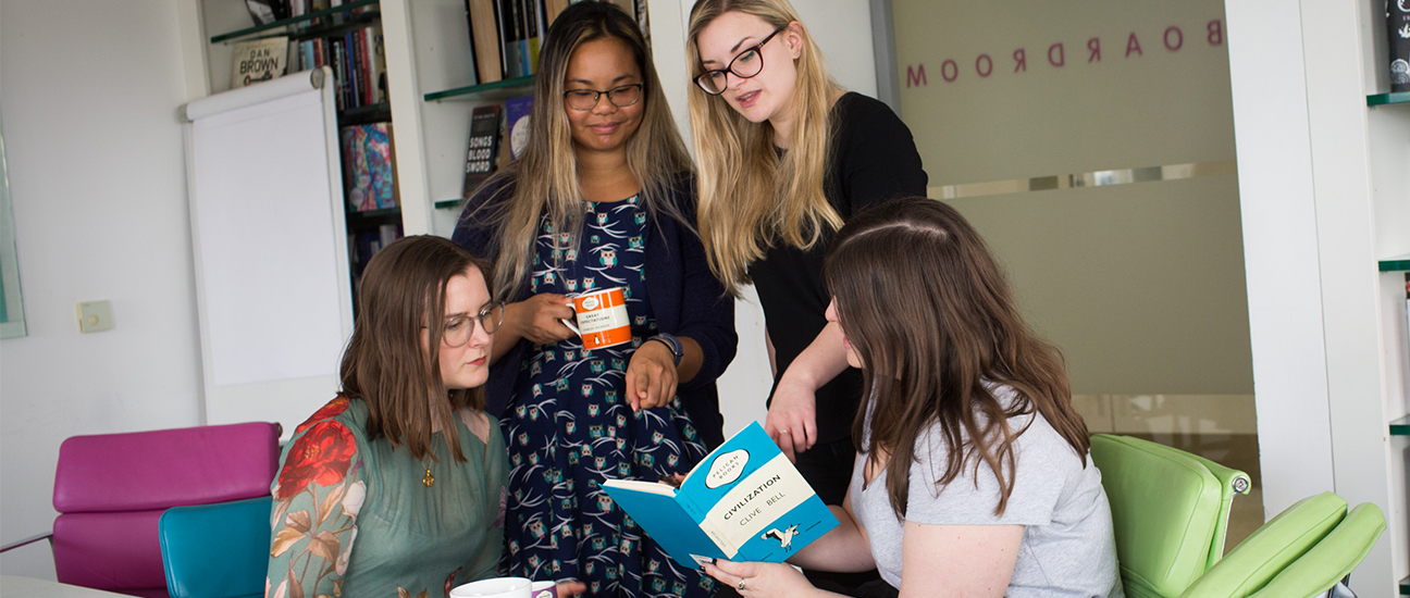 Colleagues talking and pointing at notebook in meeting